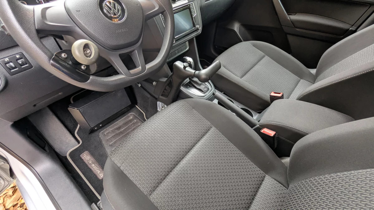 Innenansicht eines VW Caddy mit sichtbarem Lenkrad, Gangschaltung und Vordersitzen.